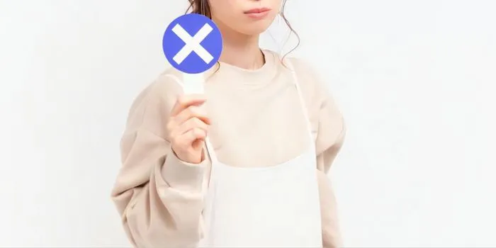 バツのカードを持つ女性